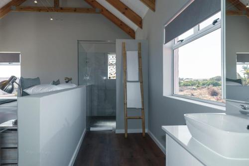 a bathroom with a white sink and a window at Blue Bay Lodge in Saldanha