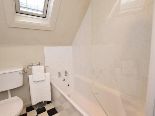 a white bathroom with a toilet and a bath tub at 3 Bed in Eastbourne 57383 in Alfriston