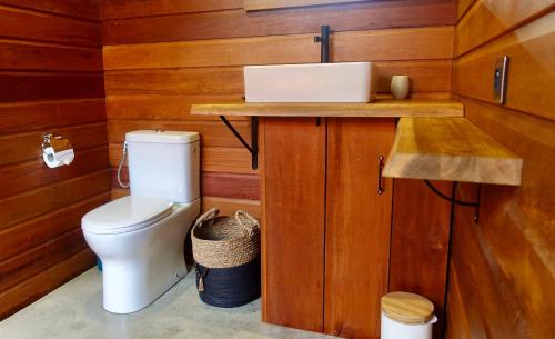 a bathroom with a toilet and a wooden wall at Kaya Lodge in Basse-Pointe