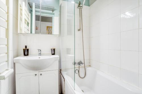 La salle de bains blanche est pourvue d'un lavabo et d'une douche. dans l'établissement Chic Appartement Climatisé à 10 Minutes de Paris: Confort et Élégance, à Maisons-Alfort