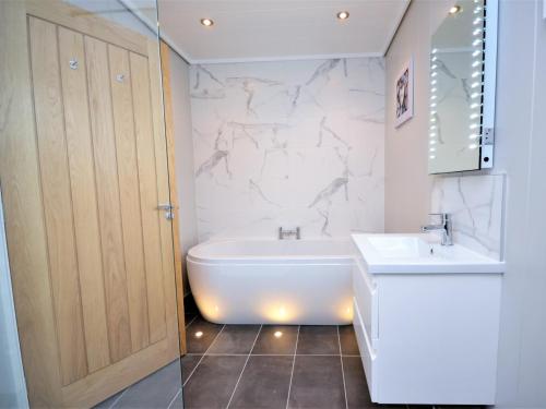 La salle de bains est pourvue d'une baignoire blanche et d'un lavabo. dans l'établissement 1 Bed in Conwy 60294, à Llangelynin