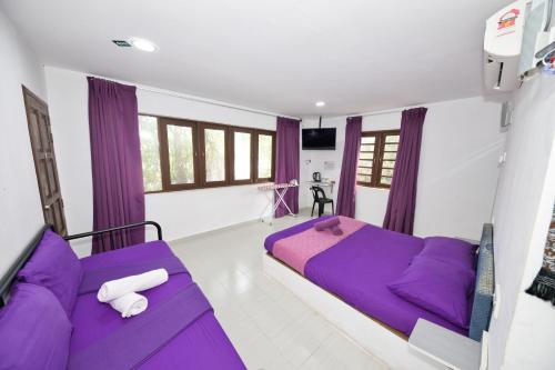 een slaapkamer met paarse bedden en paarse gordijnen bij OYO 90908 Noor Arfa River Chalet in Kuala Terengganu