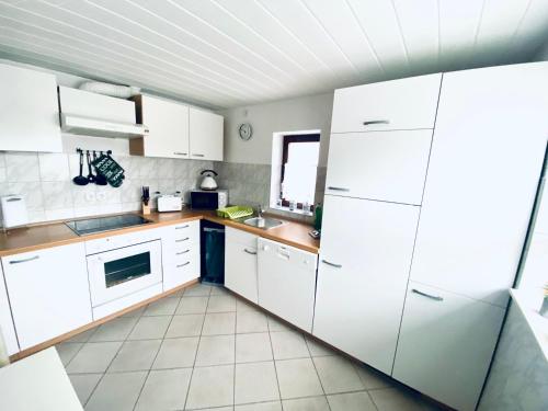 a kitchen with white cabinets and a sink at KAPITÄNS HUS 1 - Sauna, großer Garten, 400m zum Strand in Graal-Müritz