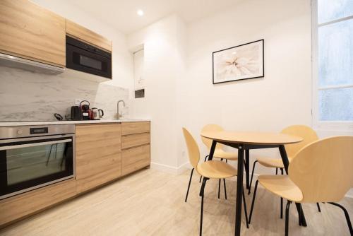 une cuisine avec une table et des chaises dans une pièce dans l'établissement Vignature REIMS - Cathédrale, à Reims