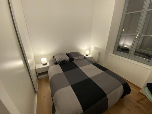 una camera con un letto bianco e nero e una finestra di Royat : Superbe appartement en face des Thermes a Royat