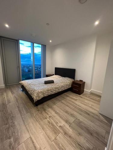 a bedroom with a bed and a large window at cozy 2 Bed Flat free parking, Manchester City Centre in Manchester