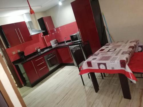 een keuken met rode kasten en een tafel met een tafel sidx sidx sidx bij Cosy appartement only family à Gueliz in Marrakesh