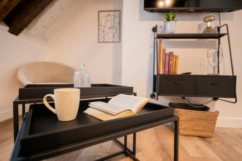a black desk with a book and a coffee mug at Le Laurencin Sens - Le Comble - Cœur de ville in Sens
