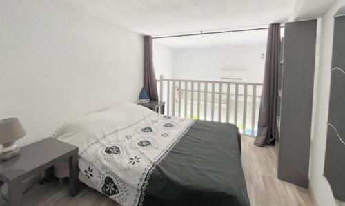 une chambre avec un lit et un bureau et un balcon dans l'établissement Agréable maison avec terrasse et piscine collective -6PQ32, au Barcarès