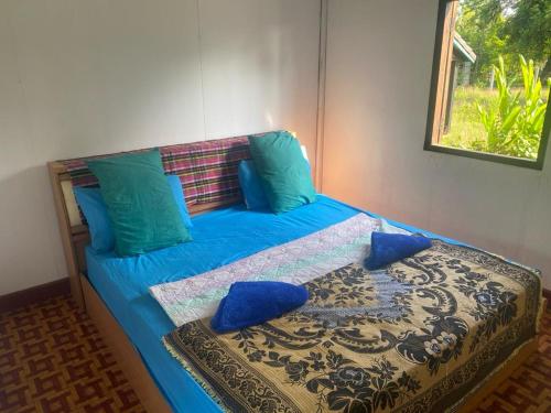 a blue bed with blue pillows and a window at King Kong Restaurant and Bungalows in Muang Không