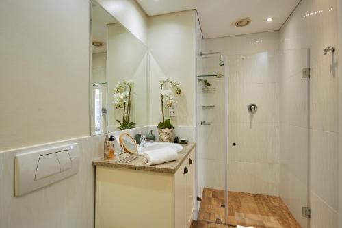 a bathroom with a shower and a sink and a mirror at Parama 102 in Cape Town