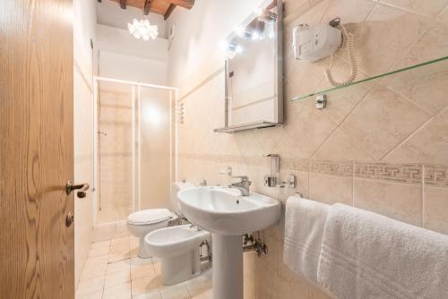 a white bathroom with a sink and a toilet at Le Masse in Greve in Chianti