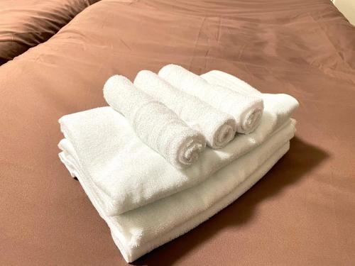 4 asciugamani bianchi sono impilati su un letto di SAKURAHOTEL Fukuoka Hatata self check in a Fukuoka
