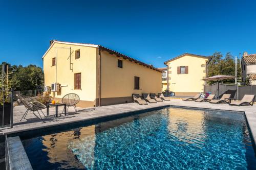 einen Pool mit Stühlen, einen Tisch und ein Haus in der Unterkunft Casa Olika in Buzet