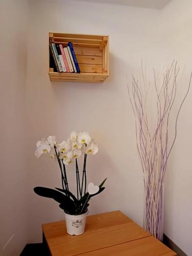 a vase of flowers on a table with a shelf at Casa Longhi in Orta San Giulio