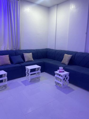 sala de estar con sofá azul y 2 mesas en الجامعين ستار en Al Ahsa