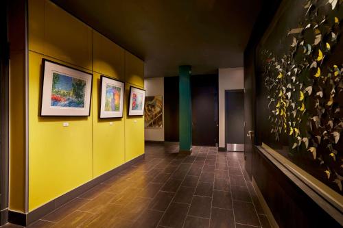 a hallway with yellow walls and paintings on the wall at The Barnes San Francisco, Tapestry Collection by Hilton in San Francisco
