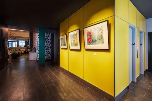 un pasillo con paredes amarillas y cuadros en las paredes en The Barnes San Francisco, Tapestry Collection by Hilton, en San Francisco