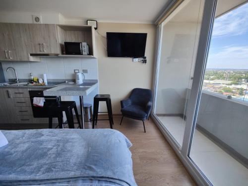 a room with a bed and a kitchen with a window at Depto Full Equipado en Centro de Chillán con Estacionamiento 10 in Chillán