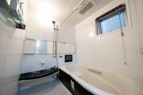 La salle de bains blanche est pourvue d'une baignoire et d'un lavabo. dans l'établissement Shinokubo guest house, à Tokyo