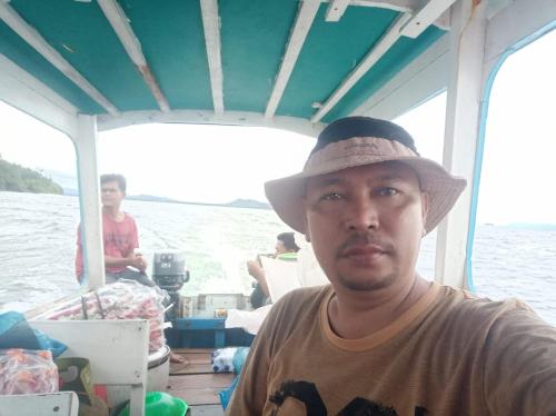 D' pamor Homestay في Halangan: رجل يرتدي قبعة يجلس على قارب