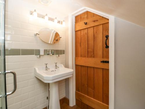 baño con lavabo y puerta de madera en The Old Bakehouse, en Leominster
