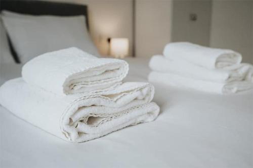 a group of white towels stacked on a bed at Westminster Luxury Liverpool Apartment with Free Parking in Liverpool