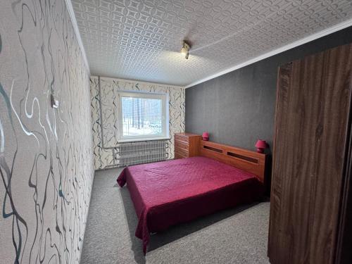 ein Schlafzimmer mit einem roten Bett und einem Fenster in der Unterkunft Real appartments in Visaginas