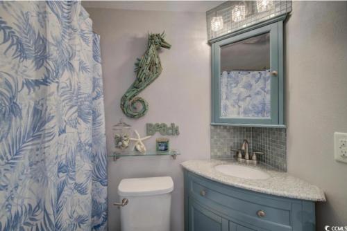 een badkamer met een wastafel en een zeepaardje aan de muur bij Seaside Elegance Your Coastal Getaway in Myrtle Beach