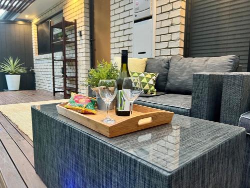 uma mesa com uma garrafa de vinho e dois copos em Private Gem in Pacific Pines em Gold Coast