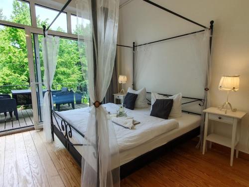 1 dormitorio con cama con dosel y balcón en DEUTSCHE OSTSEEVILLA - große Villa mit Sauna, Spielplatz, PKW-Stellplätze, großer Garten, en Rostock