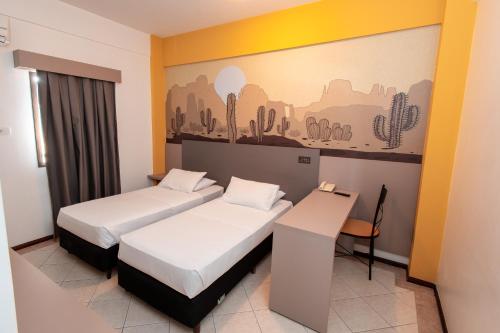 a hotel room with two beds and a desk at ibis Styles Presidente Prudente Portal D'Oeste in Presidente Prudente