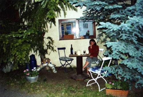 una mujer sentada en una mesa frente a una casa en Ferienhaus Hofmann Hainrode, 