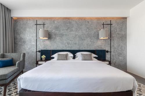 a bedroom with a large white bed and a chair at Hotel Vellita Siem reap in Siem Reap