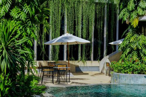 a table and chairs with an umbrella next to a pool at Hotel Vellita Siem reap in Siem Reap