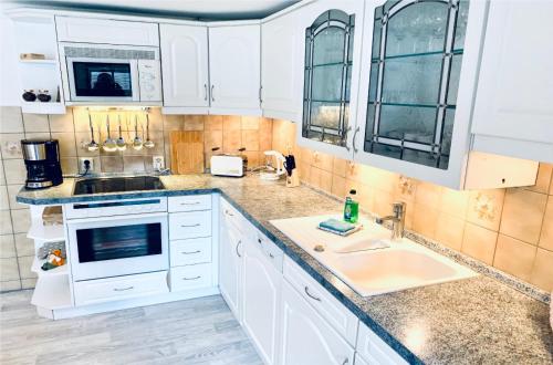 a kitchen with white cabinets and a sink at KAPITÄNS HUS - traditionelles Reethaus strandnah, Sauna, großer Garten, PKW-Stellplätze in Graal-Müritz
