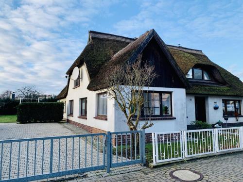 a house with a thatched roof and a fence at KAPITÄNS HUS - traditionelles Reethaus strandnah, Sauna, großer Garten, PKW-Stellplätze in Graal-Müritz