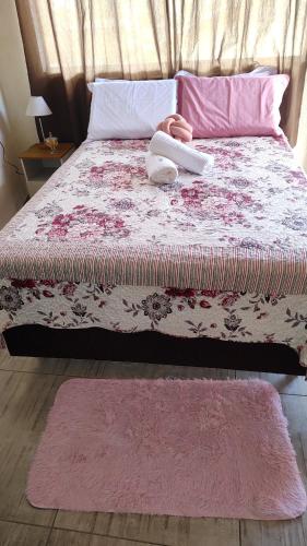 a bedroom with a bed with a pink and white blanket at Chalé rosa in Resende