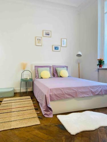 una camera da letto con un grande letto con lenzuola rosa e cuscini gialli di Appartement moderne Quartier Saint Lazare a Parigi