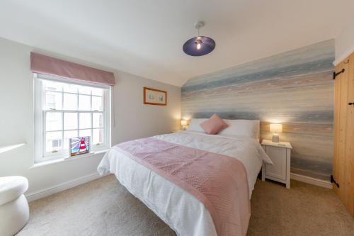 a bedroom with a bed with a painting on the wall at Angel Cottage in Southwold