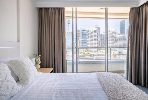 a bedroom with a bed and a large window at Spectacular Darling Harbour View Apartment & Parking in Sydney