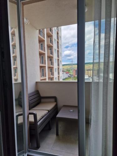 a balcony with a bench and a table and a window at Blue apartment nearby Amethyst & Vivo Mall in Floreşti