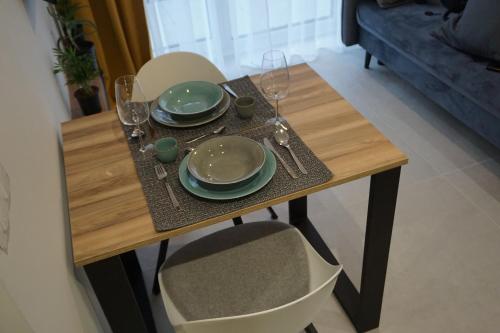 a wooden table with plates and wine glasses on it at Apartamenty Czarne Owce in Szklarska Poręba