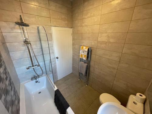 a bathroom with a tub and a toilet and a shower at Spacious 4-Bedroom House in Manchester in Manchester