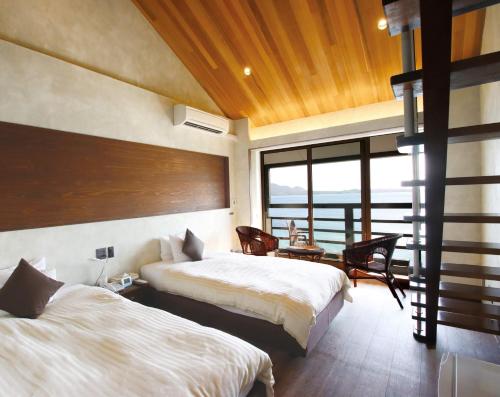 a bedroom with two beds and a view of the ocean at Petit Resort Native Sea Amami in Tatsugo