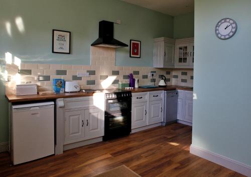 a kitchen with white cabinets and a black dishwasher at Finest Retreats - No 3 Meynell Mews in Breedon on the Hill
