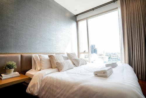a large bed in a room with a large window at Thonglor Modern Luxury Condo in Bangkok