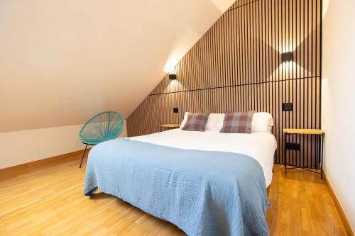ein Schlafzimmer mit einem Bett und einem blauen Stuhl in der Unterkunft VUT en centro histórico de Burgos con parking incluido ATUAIRE in Burgos