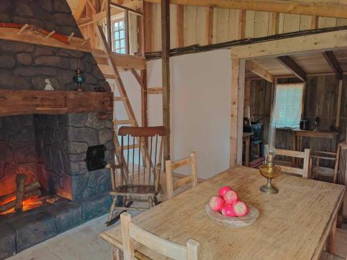 una mesa de madera en una habitación con chimenea de piedra en La petite maison dans la prairie The country House 56, en Campénéac