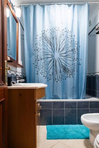 a bathroom with a blue shower curtain and a tub at Penthouse Olhão with terrace in Olhão